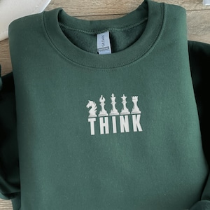 Può includere: Una felpa verde scuro con un ricamo bianco di pezzi degli scacchi e la parola "THINK".