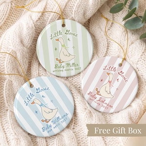 Puede incluir: Tres adornos redondos de cerámica con cordones dorados. Cada uno presenta una ilustración de un ganso, rayas verticales y el texto: Little Goose, Baby Miller arriving march 2027, Little Goose, Baby Williams due april 2027 y Little Goose, Baby Johnson arriving 2027.