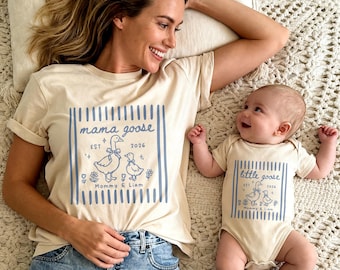 May include: A beige t-shirt and onesie set with matching blue goose graphic. The t-shirt reads "mama goose" with "EST 2026" and the onesie says "little goose". Both have a goose and duckling design.