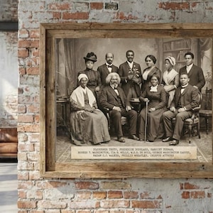 May include: A framed sepia-toned photograph featuring a group of historical figures. The image is in a rustic wooden frame and hangs on a brick wall. The photograph includes Sojourner Truth, Frederick Douglass, and others. Text at the bottom identifies the individuals.