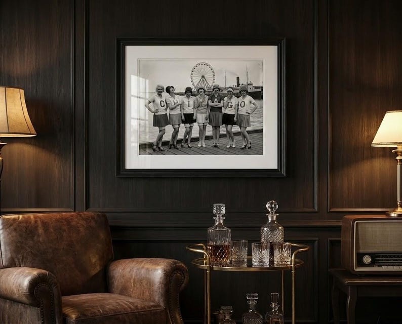 May include: Black and white framed photograph of a group of people standing in front of a Ferris wheel. The photograph is hanging on a dark wood paneled wall. A leather armchair, a lamp, and a bar cart with decanters and glasses are in the foreground.