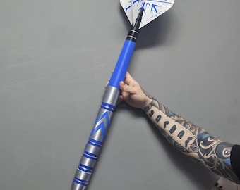 May include: A dart with white and blue "ICEMAN" flights. The dart has a blue and silver barrel with a silver tip. The dart is held against a gray background.
