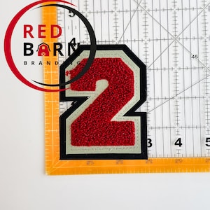 Puede incluir: Parche de fieltro rojo número dos con contorno blanco y respaldo negro. El parche mide 3,5 pulgadas de ancho y 2,5 pulgadas de alto.