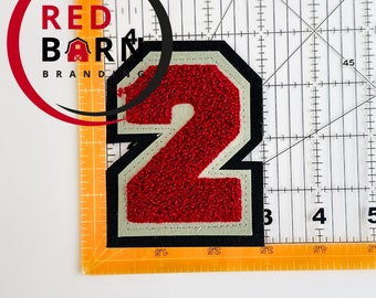 May include: Red felt number two patch with white outline and black backing. The patch is 3.5 inches wide and 2.5 inches tall.
