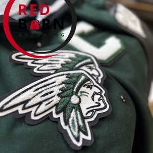 May include: Green and white embroidered patch of an American Indian with a feathered headdress. The patch is sewn onto a green fabric jacket with the text "RED BARN BRANDING" in a red circle.