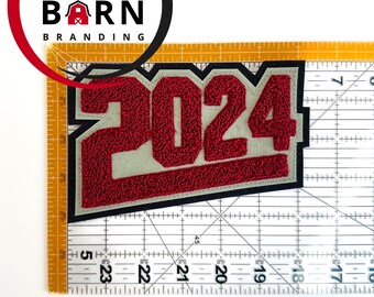 May include: Red and white 2024 patch with a black outline. The patch is made of a fuzzy material and is about 12.5 cm wide.