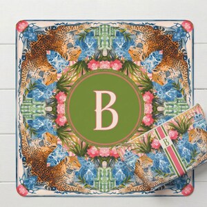Puede incluir: Alfombra decorativa cuadrada con un c&iacute;rculo verde con la letra "B" en el centro. La alfombra tiene un dise&ntilde;o floral y de leopardo con detalles en azul y rosa. Tambi&eacute;n se ve una bolsa rectangular a juego.