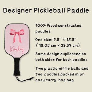 May include: A pink pickleball paddle with a pink bow and the name "Kinsley" written on it. The paddle is made of 100% wood and measures 7.5 inches by 15.5 inches (19.05 cm x 39.37 cm). It comes with two plastic wiffle balls and an easy carry bag.