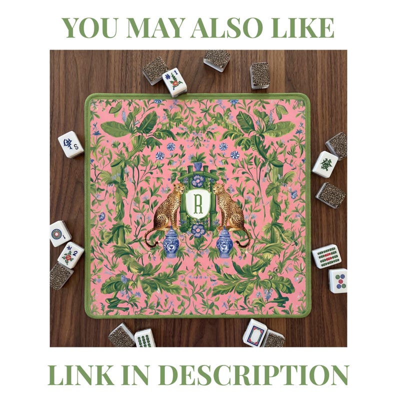 May include: Pink mahjong mat with a green border, featuring a botanical design with two cheetahs, blue vases, and the letter "R". The mat is surrounded by mahjong tiles. The text "YOU MAY ALSO LIKE" and "LINK IN DESCRIPTION" are also visible.