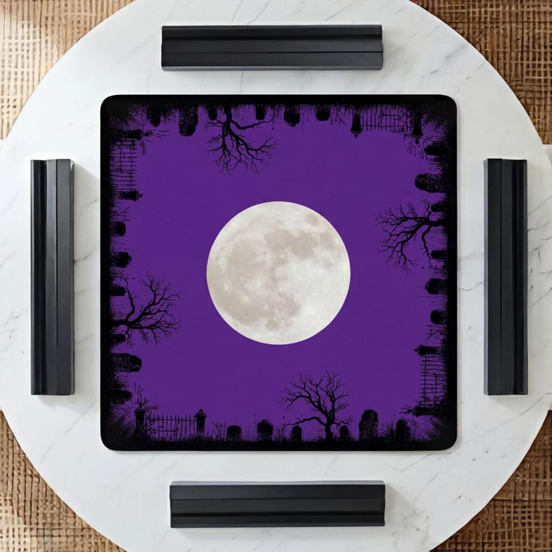 K&ouml;nnte beinhalten: Eine quadratische Spielmatte mit einem leuchtend violetten Hintergrund und einem gro&szlig;en, zentrierten Vollmond. Der Rand ist mit einer schwarzen Silhouette eines Friedhofs verziert, die Grabsteine, kahle B&auml;ume und Eisenz&auml;une zeigt.