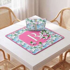 May include: A square game mat and a matching zippered pouch featuring a tropical palm tree pattern in shades of blue, green, and pink. The mat has a large pink central hexagon with a white letter B, and small white and green game tiles are scattered.