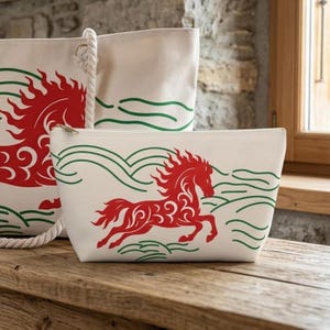 May include: A cream-colored canvas tote bag and a matching zippered pouch, both featuring a stylized red horse graphic surrounded by green wavy lines. The tote bag includes thick white rope handles attached with metal rings.