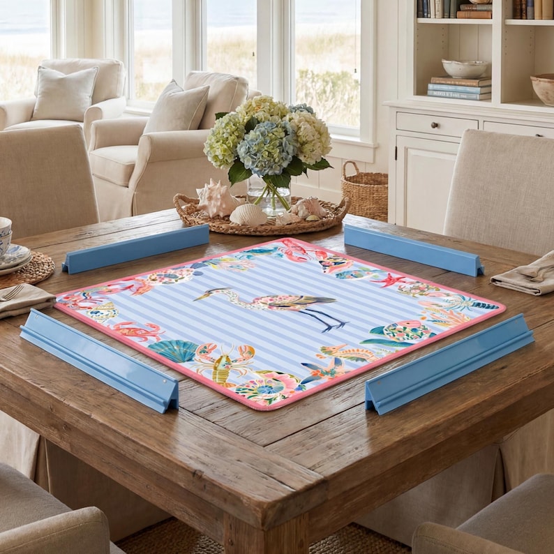 May include: A square puzzle mat featuring a light blue and white striped pattern with a central heron illustration, surrounded by a border of colorful sea life including crabs, starfish, and shells, framed by four blue plastic puzzle edge pieces.