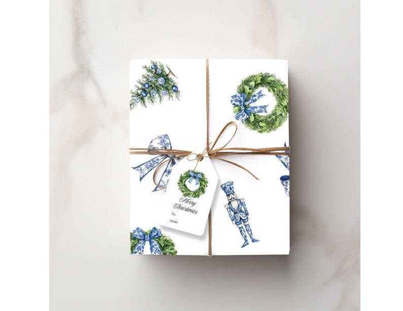 Puede incluir: Un regalo rectangular envuelto en papel blanco con un patr&oacute;n de coronas verdes, lazos azules y cascanueces. El paquete est&aacute; atado con cuerda marr&oacute;n e incluye una etiqueta blanca con una ilustraci&oacute;n de corona y el texto Merry Christmas.