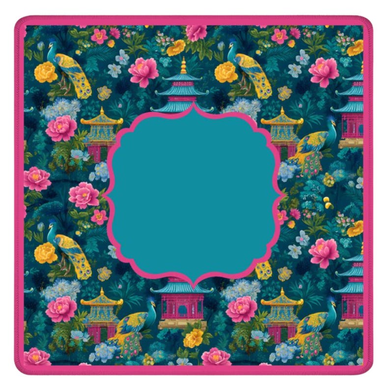 Op de afbeelding: Een vierkante mat met een donkergroenblauwe achtergrond met een herhalend patroon van blauwe en gele pauwen, roze pioenrozen en blauwe pagodes. De mat heeft een effen roze rand en een groot, centraal, geschulpt kader in groenblauw.