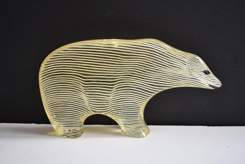 K&ouml;nnte beinhalten: Eine gelbe Glasskulptur eines B&auml;ren mit wei&szlig;en Streifen. Der B&auml;r steht auf allen Vieren und hat ein schlichtes Design.