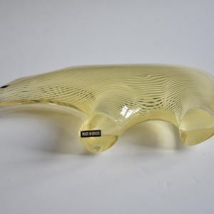 K&ouml;nnte beinhalten: Eine gelbe Glasskulptur eines B&auml;ren mit einem gestreiften Muster. Der B&auml;r steht auf allen Vieren und hat ein Etikett an der Seite, auf dem "Made in Italy" steht.
