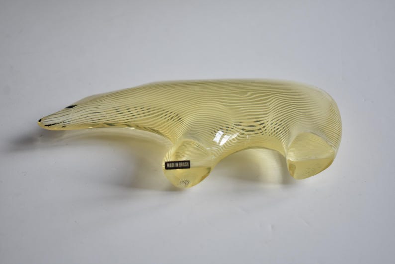 K&ouml;nnte beinhalten: Eine gelbe Glasskulptur eines B&auml;ren mit einem gestreiften Muster. Der B&auml;r steht auf allen Vieren und hat ein Etikett an der Seite, auf dem "Made in Italy" steht.
