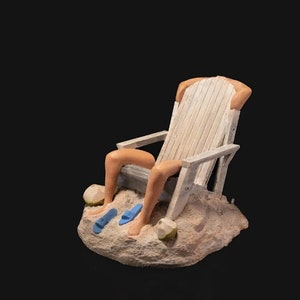 May include: A white wooden beach chair with a person's legs sticking out of it. The chair is sitting on a sandy base with two blue flip flops and two coconuts.