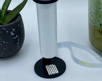 Peut inclure: Un bâton lumineux vert avec un cube en plastique transparent sur le dessus. Le cube contient un symbole vert. Le bâton lumineux a une poignée blanche et une base noire avec le texte "NCT 127" dessus.