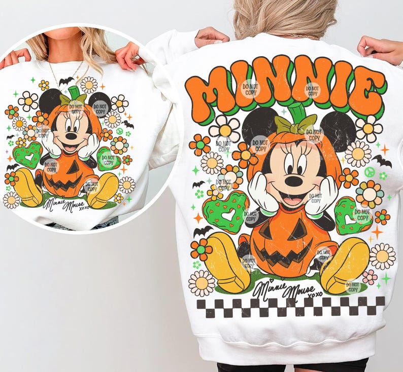 May include: White sweatshirt featuring a Minnie Mouse design in a pumpkin costume. The design includes orange, yellow, green, and black elements, with floral and heart accents. The text "MINNIE" and "Minnie Mouse xoxo" are also visible.