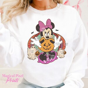 May include: White sweatshirt with a Halloween Minnie Mouse design. Minnie Mouse is holding a jack-o'-lantern, with ghosts and bats. The design includes the text "DO NOT COPY" and "Magical Pixel Prints".