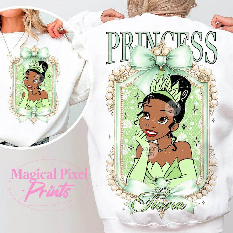 May include: White sweatshirt with a green and gold princess design. The design features a cartoon princess with a crown, a green dress, and a frog. The text "Princess" is above the design, and the text "Tiana" is below the design.