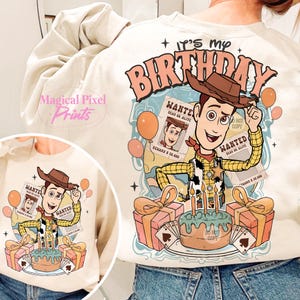 May include: A beige sweatshirt with a cartoon image of Woody from Toy Story. Woody is holding a birthday cake and a wanted poster. The text on the sweatshirt says "It's my birthday".