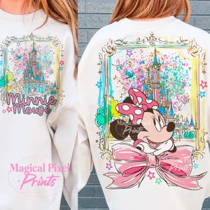 Pode incluir: Camisola branca com uma ilustra&ccedil;&atilde;o colorida de um castelo e Minnie Mouse. A frente da camisola tem o texto "Minnie Mouse" e as costas t&ecirc;m um grande gr&aacute;fico da Minnie Mouse com um la&ccedil;o rosa. A camisola tem um design emoldurado com estrelas.