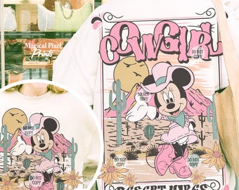 May include: A white t-shirt with a pink and white graphic design featuring a cartoon mouse wearing a cowboy hat and boots. The graphic also includes cacti, a sunset, and the text "COWGIRL" and "DESERT VIBES ON MY MIND".