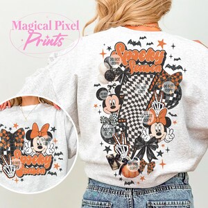 K&ouml;nnte beinhalten: Ein hellgraues Sweatshirt mit einem Halloween-Motiv. Das Design enth&auml;lt den Text "Spooky Season", Mickey und Minnie Mouse, Schleifen und ein Schachbrettmuster. Das Design umfasst auch Flederm&auml;use, Sterne und K&uuml;rbisse.