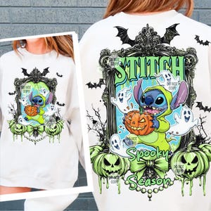 May include: White sweatshirt featuring a Halloween-themed graphic. The design includes Stitch in a green costume holding a jack-o'-lantern, surrounded by ghosts and pumpkins. The words "Stitch" and "Spooky Season" are also visible.