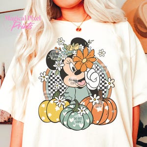 May include: A white t-shirt with a graphic of a cartoon mouse wearing a flower crown and holding a pumpkin. The mouse is surrounded by pumpkins and flowers. The text "DO NOT COPY" appears multiple times on the graphic.