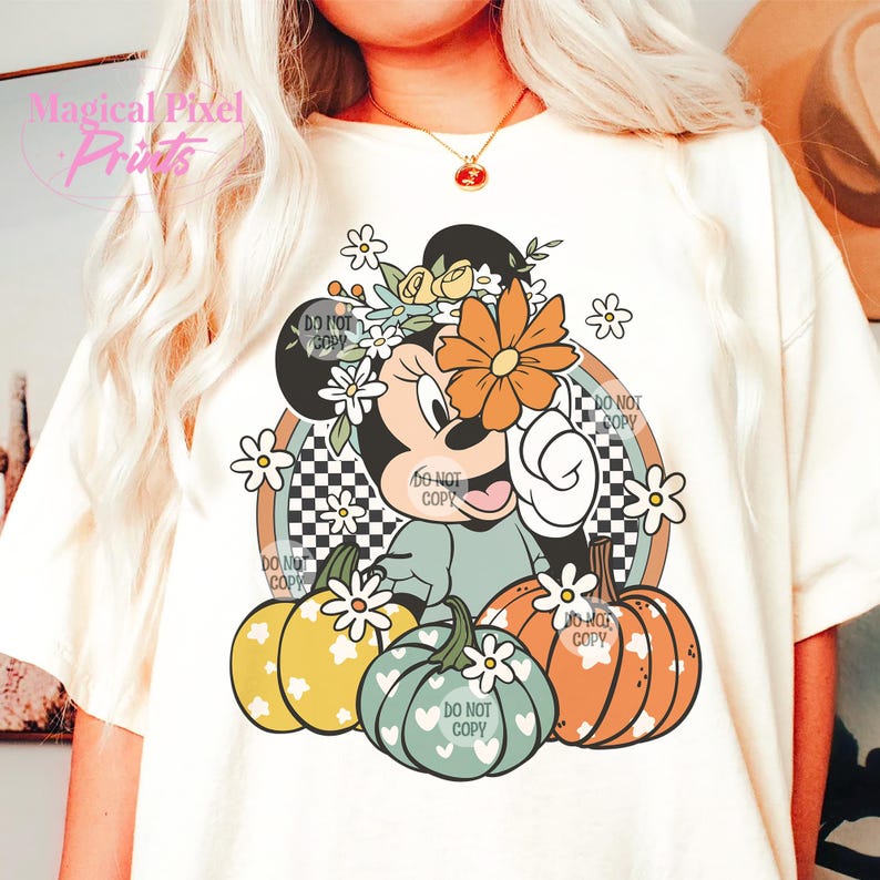 May include: A white t-shirt with a graphic of a cartoon mouse wearing a flower crown and holding a pumpkin. The mouse is surrounded by pumpkins and flowers. The text "DO NOT COPY" appears multiple times on the graphic.