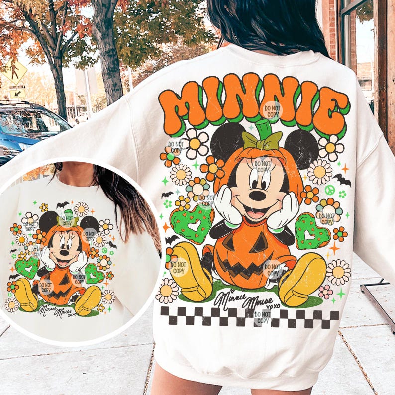 May include: Cream-colored sweatshirt featuring a Halloween-themed Minnie Mouse design. The graphic includes Minnie Mouse dressed as a pumpkin, surrounded by flowers, hearts, and the word "MINNIE" in orange and green. A black and white checkered pattern is at the bottom.