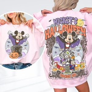 Może przedstawiać: Jasnor&oacute;żowa bluza z motywem Halloween. Prz&oacute;d przedstawia Myszka Miki jako wampira, a tył "Mickey's Halloween". Projekt zawiera nagrobek, nietoperze i dynię. Widoczne są r&oacute;wnież słowa "Trick or Treat".