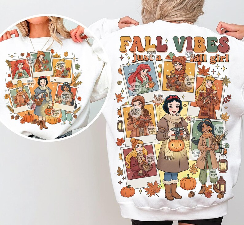 May include: White sweatshirt featuring a colorful graphic of cartoon princesses in fall attire. The design includes pumpkins, leaves, and the text "FALL VIBES just a fall girl". The princesses are depicted in polaroid-style frames.