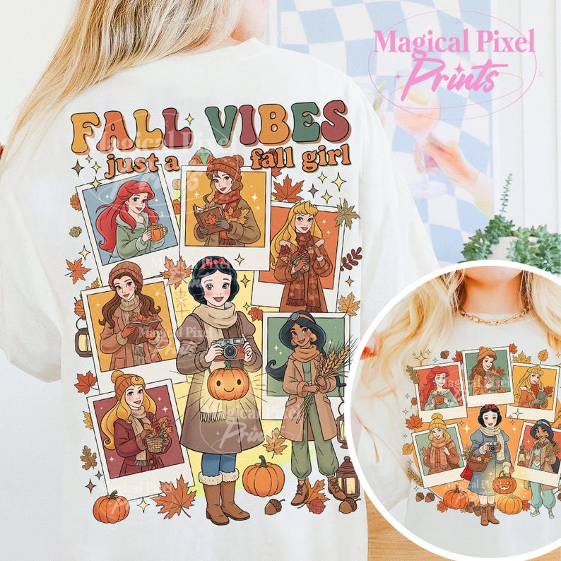 May include: Cream-colored t-shirt with a graphic featuring cartoon princesses in fall attire. The shirt has the text "FALL VIBES just a fall girl" in orange and brown. The design includes pumpkins and autumn leaves.