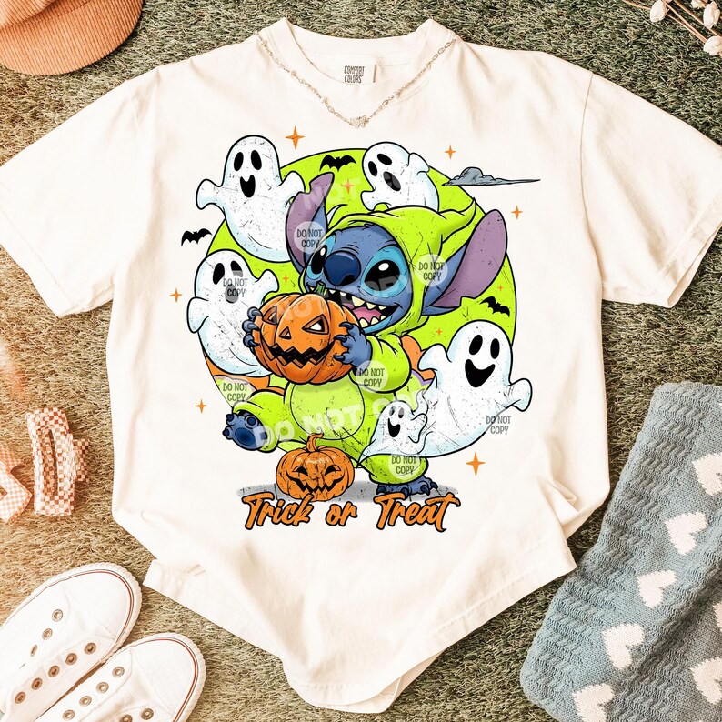 Puede incluir: Camiseta blanca con un dise&ntilde;o de Halloween. El dise&ntilde;o presenta a Stitch disfrazado de verde sosteniendo una calabaza, rodeado de fantasmas y el texto "Trick or Treat". La camiseta tiene cuello redondo y mangas cortas.
