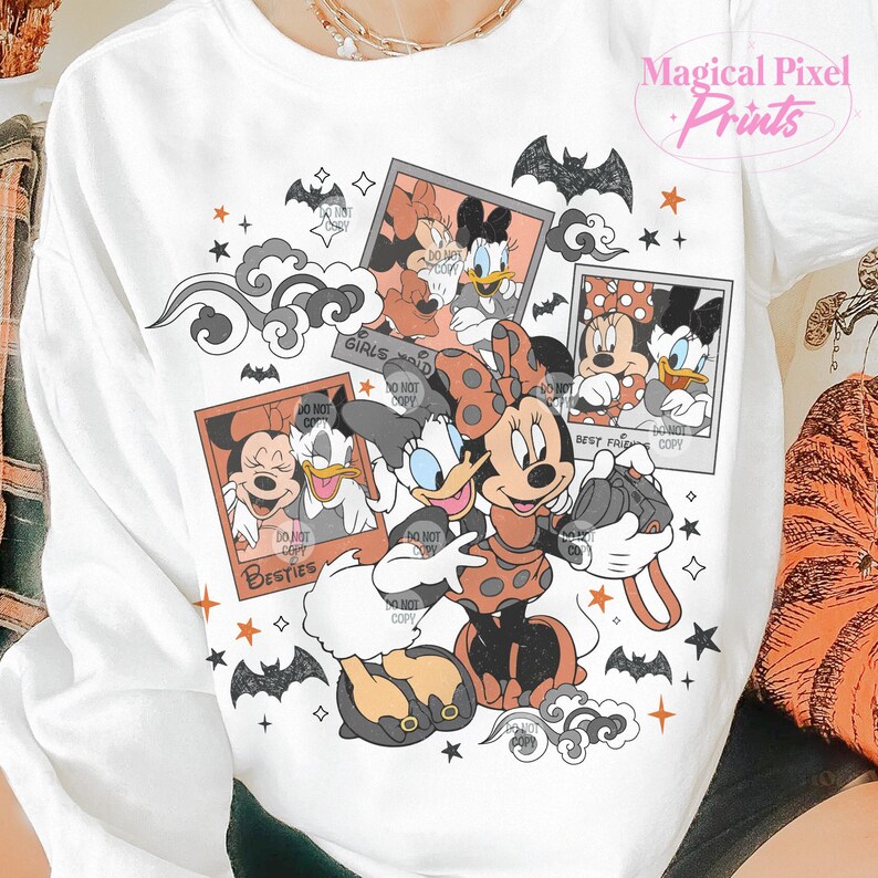 Op de afbeelding: Witte trui met een grafische print van Mickey Mouse en Minnie Mouse in Halloween-kostuums. De print bevat de tekst "Girls just wanna have fun" en "Besties".
