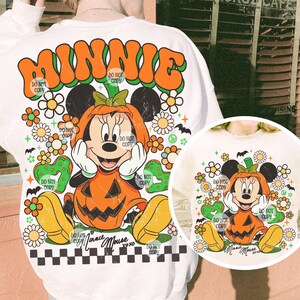 May include: White sweatshirt featuring a retro design with the word "MINNIE" in orange and green. The graphic includes Minnie Mouse dressed as a pumpkin, surrounded by flowers, bats, and the text "Do Not Copy".
