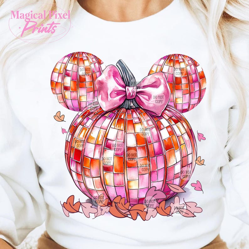 K&ouml;nnte beinhalten: Ein wei&szlig;er Pullover mit einem pinkfarbenen und orangenen K&uuml;rbisdesign. Der K&uuml;rbis ist in Form von Mickey-Maus-Ohren geformt und hat eine rosafarbene Schleife. Der K&uuml;rbis besteht aus einem Mosaik aus Quadraten und hat einen Aquarelleffekt. Um den K&uuml;rbis herum befinden sich kleine rosa und orangefarbene Bl&auml;tter.