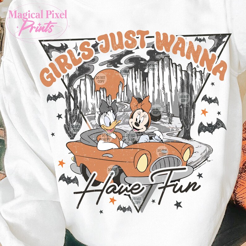 May include: A white t-shirt with a vintage-style graphic featuring two cartoon characters, a duck and a mouse, driving a red car. The text "Girls Just Wanna Have Fun" is printed in orange and black letters.