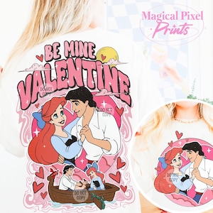 May include: White t-shirt with a pink and white graphic design featuring Ariel and Prince Eric from The Little Mermaid. The graphic says "Be Mine Valentine" in pink letters.