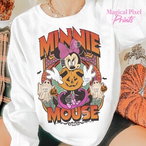 May include: White crew neck sweatshirt with a Halloween design. The graphic features Minnie Mouse, a carved pumpkin, ghosts, and the words "MINNIE MOUSE" in orange and purple. The words "DO NOT COPY" are also visible.