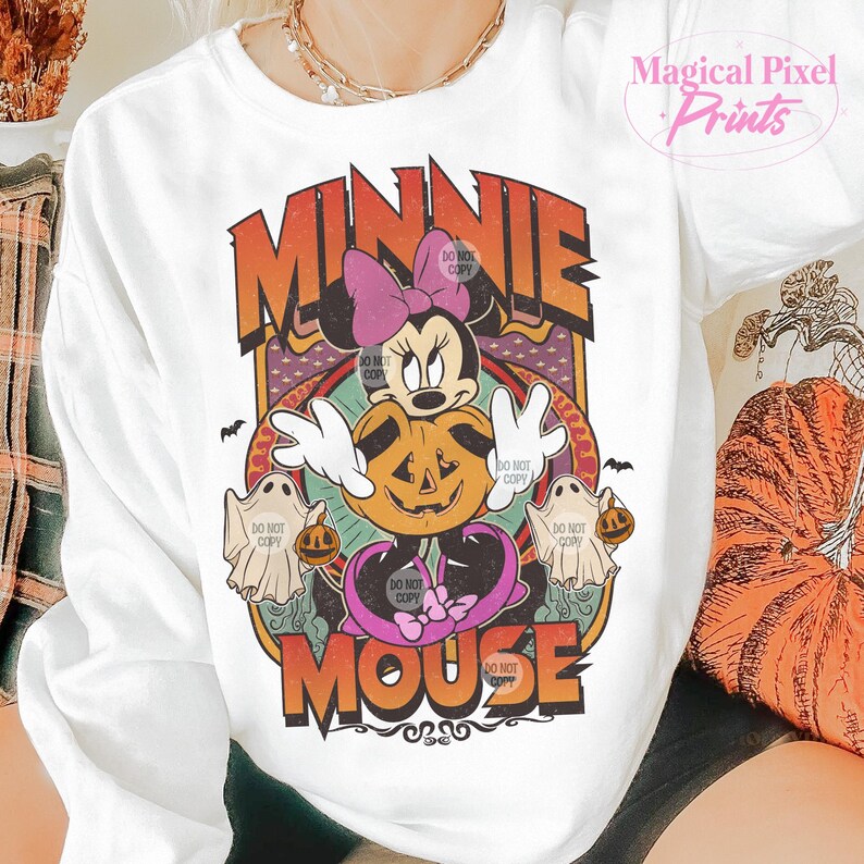 May include: White crew neck sweatshirt with a Halloween design. The graphic features Minnie Mouse, a carved pumpkin, ghosts, and the words "MINNIE MOUSE" in orange and purple. The words "DO NOT COPY" are also visible.