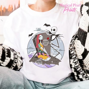 May include: A white t-shirt with a colorful illustration of Jack Skellington and Sally from the Nightmare Before Christmas. Jack is holding a red rose and Sally is sitting on a tombstone. The text "Do Not Copy" appears multiple times on the shirt.