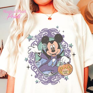 Puede incluir: Una camiseta blanca con una ilustraci&oacute;n morada y azul de Mickey Mouse vestido de vampiro sosteniendo una calabaza de Halloween. La ilustraci&oacute;n est&aacute; rodeada de un marco decorativo con estrellas y el texto "DO NOT COPY" repetido varias veces.