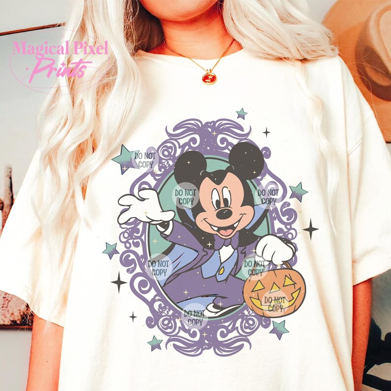 Puede incluir: Una camiseta blanca con una ilustraci&oacute;n morada y azul de Mickey Mouse vestido de vampiro sosteniendo una calabaza de Halloween. La ilustraci&oacute;n est&aacute; rodeada de un marco decorativo con estrellas y el texto "DO NOT COPY" repetido varias veces.