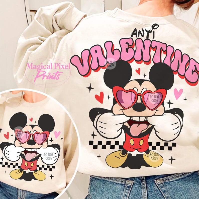 Pu&ograve; includere: Una felpa beige con una grafica rosa che dice "ANTI VALENTINE" con un cartone animato di Topolino che indossa occhiali a forma di cuore e una lingua rossa che sporge. La grafica di Topolino &egrave; su uno sfondo a scacchi con cuori rosa.